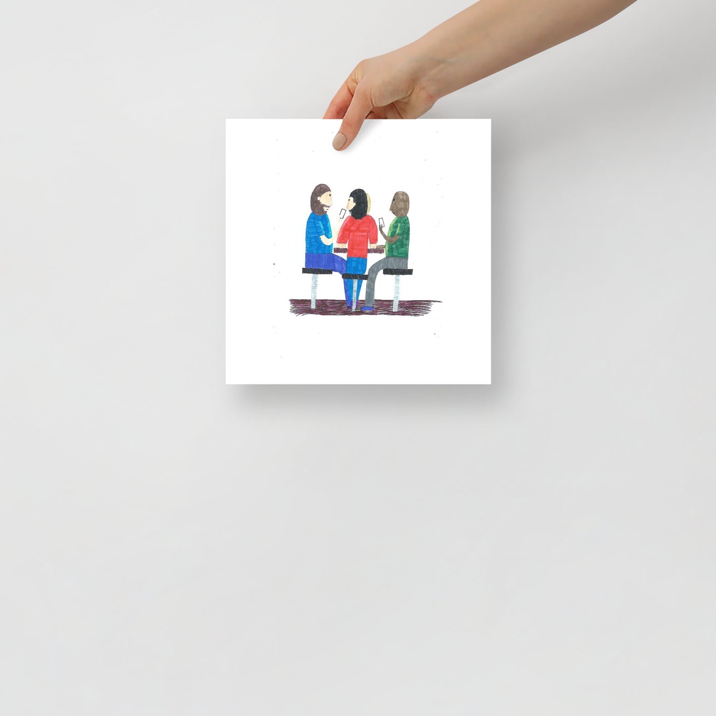 This image shows a square art print of three people seated at a table, engaging in a card game and conversation. The image conveys a sense of collaboration and connection.