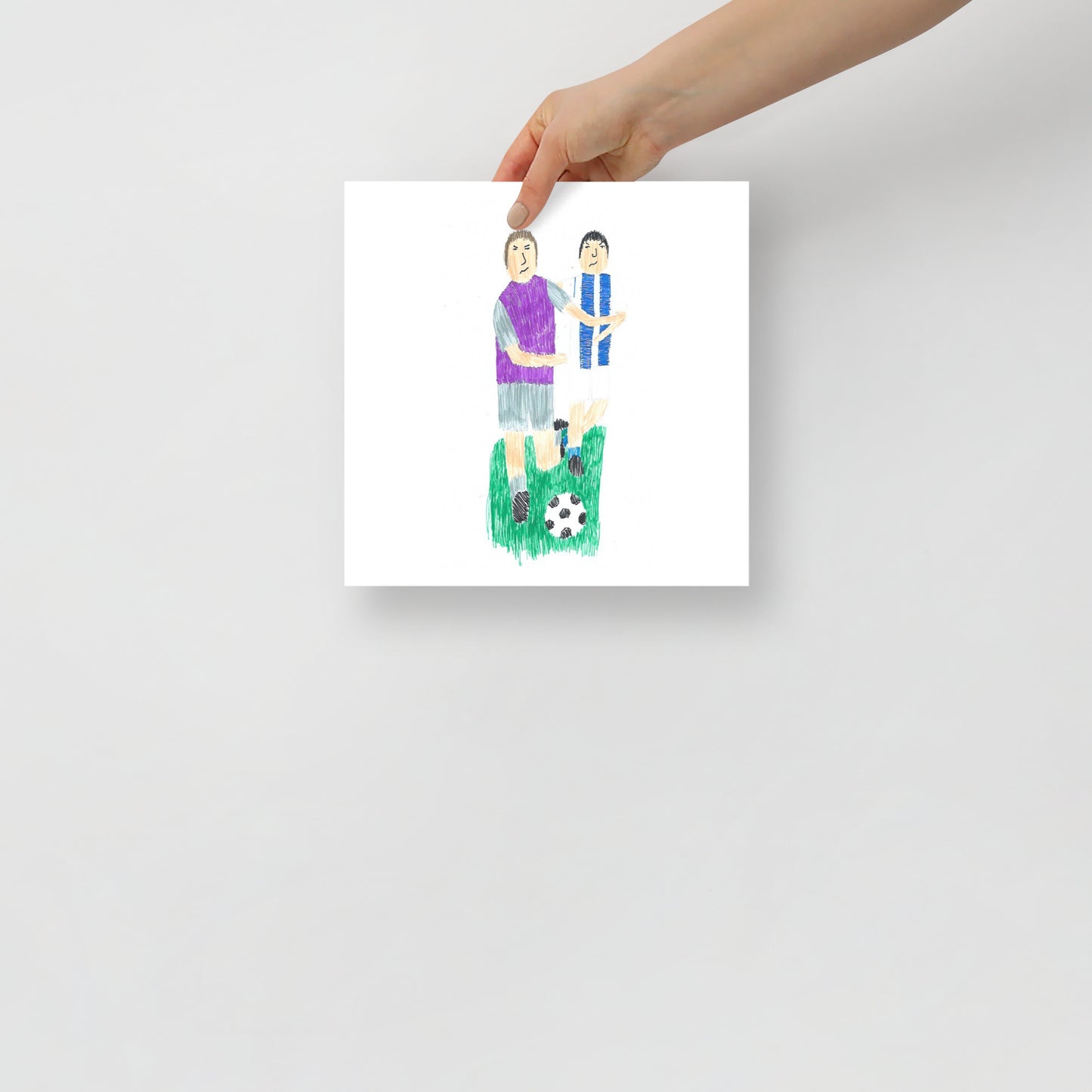 This item is an art print featuring a square artwork of two soccer players; one in a purple shirt and the other in blue and white, with a soccer ball on green grass below.