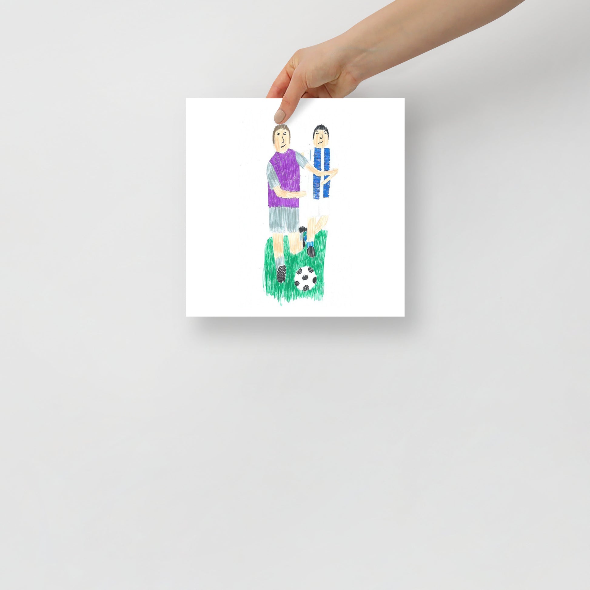 This item is an art print featuring a square artwork of two soccer players; one in a purple shirt and the other in blue and white, with a soccer ball on green grass below.