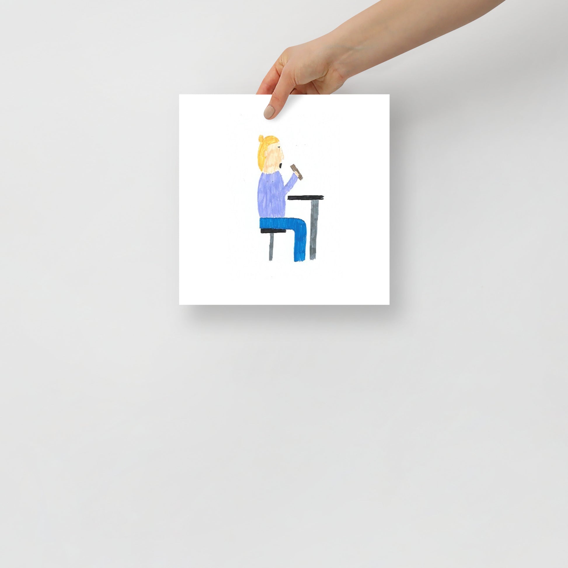This item is an art print featuring a square print featuring a child-like drawing of a person with blonde hair wearing blue, sitting at a table eating some food, emphasizing simplicity and creativity.